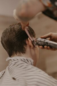 Close-up of a man getting a precise haircut, showcasing grooming tools in a barber shop.